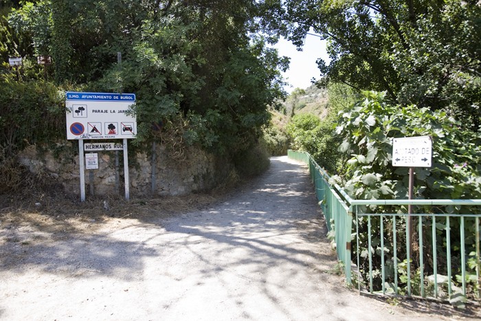 Entrada zona de La Jarra  - Saliendo del pueblo por el estadio de fútbol. Continuaremos hasta el siguiente cruce y tomaremos la carretera de San Juan hacia nuestra derecha, en un giro de 360º. En la siguiente curva sale un camino de tierra a la derecha, donde hay una señal que indica Zona de la Jarra (COMO VEMOS EN LA FOTOGRAFÍA). Continuaremos este camino de tierra buscando una senda que sale a nuestra izquierda justo antes de una antigua masía abandonada al final del camino. Continuaremos la senda buscando el cauce del río hacia nuestra derecha. Una vez en el río, remontaremos el barranco hasta llegar al charco de los Peñones, donde nos encontraremos el primer sector. 