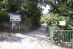 Entrada zona de La Jarra  - Saliendo del pueblo por el estadio de fútbol. Continuaremos hasta el siguiente cruce y tomaremos la carretera de San Juan hacia nuestra derecha, en un giro de 360º. En la siguiente curva sale un camino de tierra a la derecha, donde hay una señal que indica Zona de la Jarra (COMO VEMOS EN LA FOTOGRAFÍA). Continuaremos este camino de tierra buscando una senda que sale a nuestra izquierda justo antes de una antigua masía abandonada al final del camino. Continuaremos la senda buscando el cauce del río hacia nuestra derecha. Una vez en el río, remontaremos el barranco hasta llegar al charco de los Peñones, donde nos encontraremos el primer sector. 